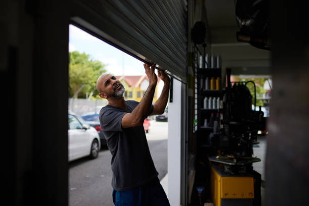 Asian male mechanic opening shutter door to car workshop Asian male mechanic starts his day by opening shutter door to car workshop door repairman men manual worker stock pictures, royalty-free photos & images