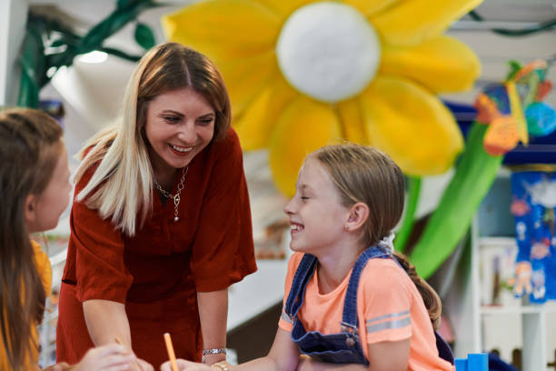 istock Creative kids during an art class in a daycare center or elementary school classroom drawing with female teacher. 1490551637