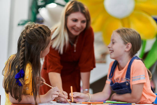 istock Creative kids during an art class in a daycare center or elementary school classroom drawing with female teacher. 1490551897