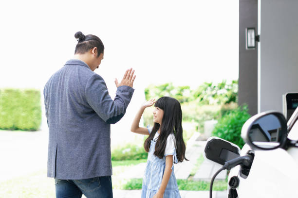 istock Progressive dad and daughter charging EV car from home charging station. 1490553642