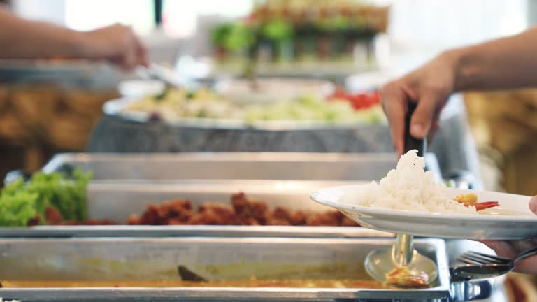 People scooping food on a Thai buffet-style.