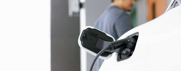 istock Focus EV charging station at home with blur progressive man in background. 1490554346