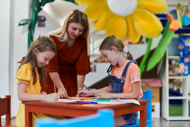 istock Creative kids during an art class in a daycare center or elementary school classroom drawing with female teacher. 1490554474