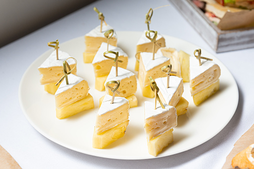 An appetizing plate of pineapple pieces and cheese canapes on skewers, perfect for any party table of snacks.