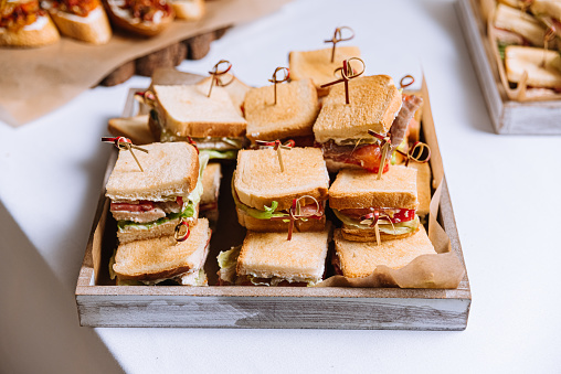 A wooden tray filled with a variety of mini sandwiches, ready to eat, for an enjoyable and fresh meal.