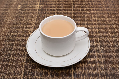 Closeup of a high quality porcelain cup on top of a white plate, ready to be filled.