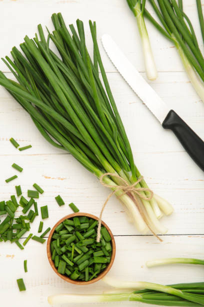istock Cut green onion on white wooden background. 1490560835