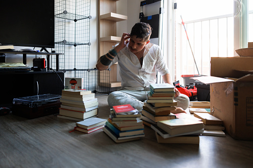 Man organizing with a purpose: decluttering for a better life, picking up books from the boxes