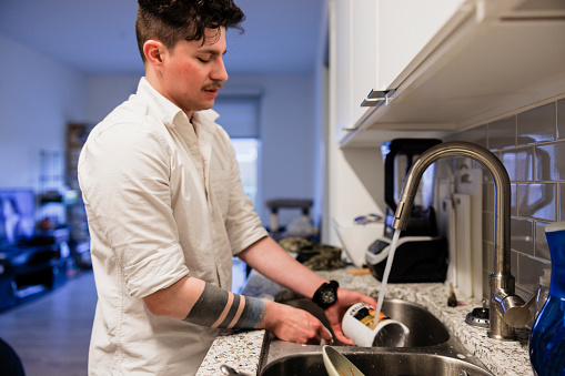 Cleaning and washing chores at home: a Hispanic man finds peace in dishwashing at home