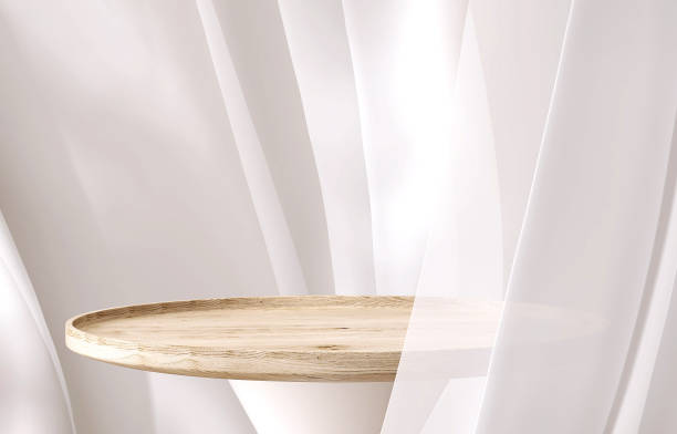 istock Empty modern round wooden podium side table in soft white blowing drapery curtain drapes in sunlight 1490561094