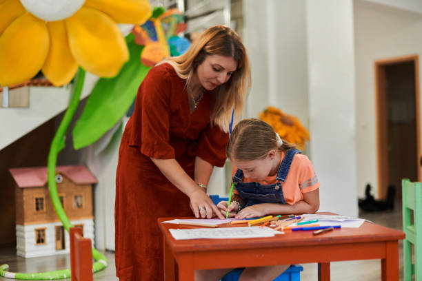 istock Creative kids during an art class in a daycare center or elementary school classroom drawing with female teacher. 1490561224