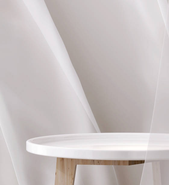 istock Empty modern glossy white round podium side table, wood leg in soft blowing drapery curtain drapes in sunlight 1490561458