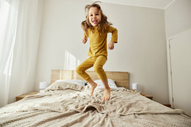 istock Carefree girl having fun while jumping on a bed. 1490563158