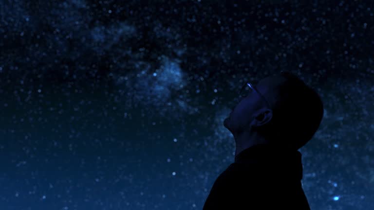 Man looking at the night sky, stars, planets, Moon and shooting stars.