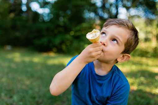 Little boy eating ice cream in a cone in the park