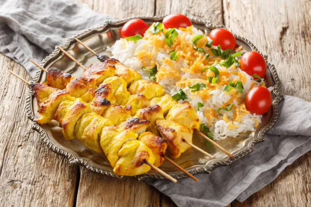 Photo of Joojeh Kabab is a deliciously tender Persian chicken kabob that has a unique saffron flavour served with rice closeup on the plate. Horizontal