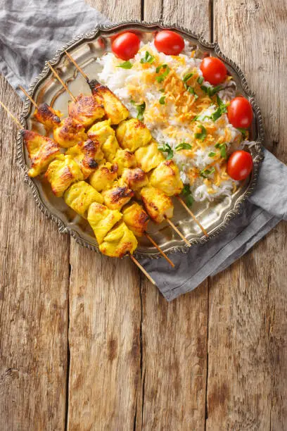 Photo of Grilled chicken kebab is known as jujeh kabab with rice closeup on the plate. Vertical top view