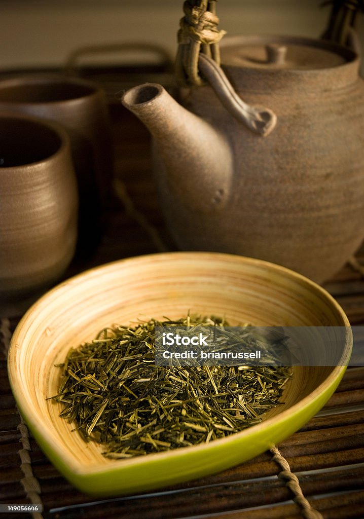 Green Tea In the foreground, a bamboo dish containing green tea with a traditional Japanese teapot (kyusu) and teacups in the background. Drink Stock Photo