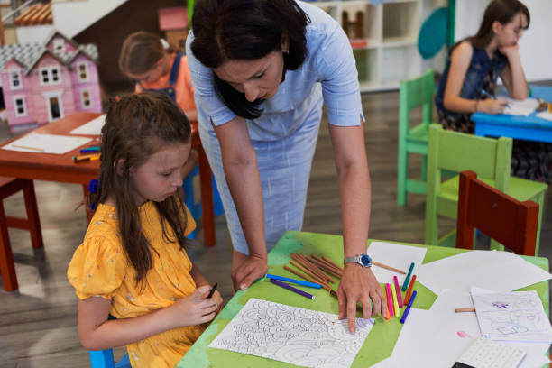istock Creative kids during an art class in a daycare center or elementary school classroom drawing with female teacher. 1490568247