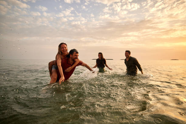 istock Cheerful couples having fun in the sea at sunset. 1490568278