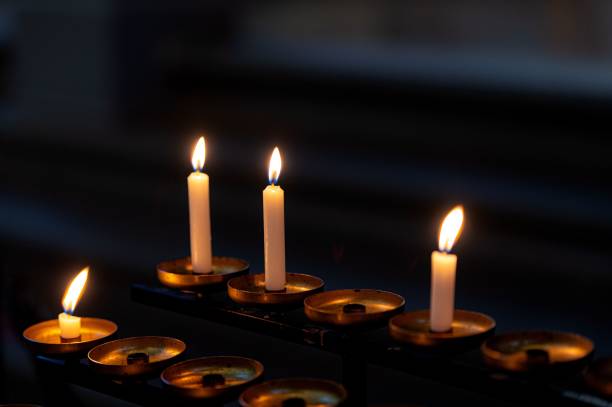 istock Flickering candles arranged in two rows on a table top, illuminated by a soft light 1490568409