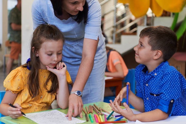 istock Creative kids during an art class in a daycare center or elementary school classroom drawing with female teacher. 1490568762