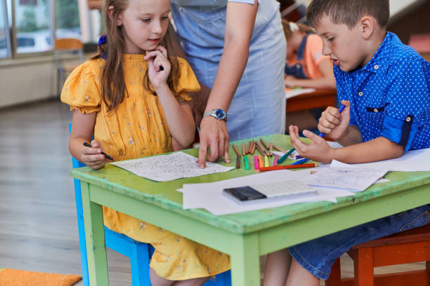 istock Creative kids during an art class in a daycare center or elementary school classroom drawing with female teacher. 1490569726