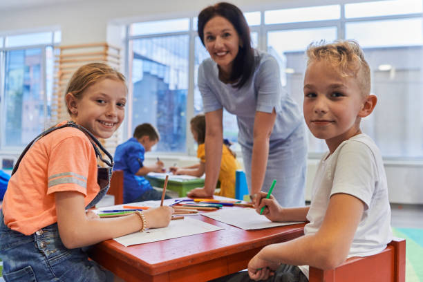 istock Creative kids during an art class in a daycare center or elementary school classroom drawing with female teacher. 1490575241