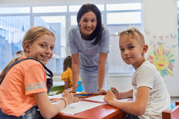 istock Creative kids during an art class in a daycare center or elementary school classroom drawing with female teacher. 1490576484