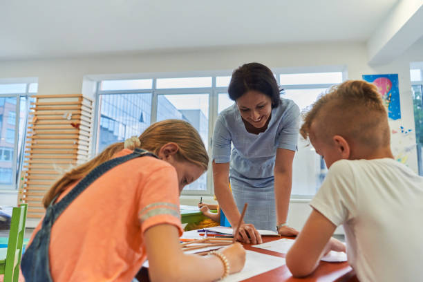 istock Creative kids during an art class in a daycare center or elementary school classroom drawing with female teacher. 1490576831