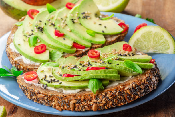 istock Avocado toast - bread with avocado slices, pieces chilli pepper and black sesame on blue plate closeup. 1490577201