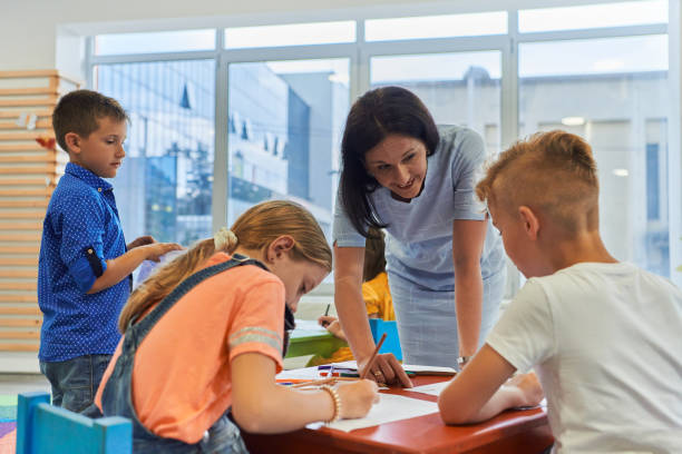 istock Creative kids during an art class in a daycare center or elementary school classroom drawing with female teacher. 1490577623