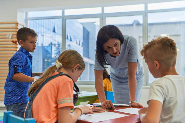istock Creative kids during an art class in a daycare center or elementary school classroom drawing with female teacher. 1490578284