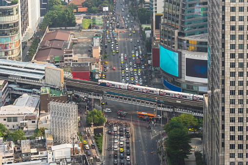 Transport on the crossroad in Bangkok at rush hour. Traffic of vehicles - cars, bikes and train on highway and intersection street urban high-angle view