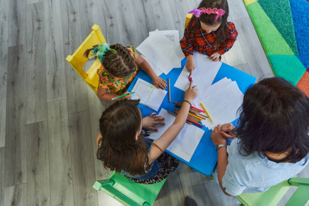 istock Creative kids during an art class in a daycare center or elementary school classroom drawing with female teacher. 1490580348