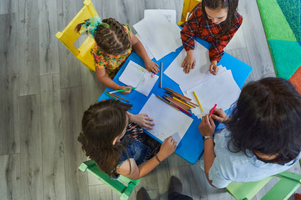 istock Creative kids during an art class in a daycare center or elementary school classroom drawing with female teacher. 1490580499
