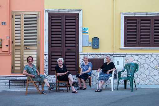 Castro, Italy. 07 02 2019. Caucasian elderly women sitting getting cool in summer at sunset.