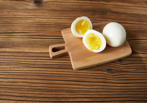 Boiled eggs on a cutting board on a wooden background, top view