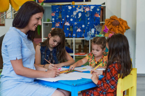 istock Creative kids during an art class in a daycare center or elementary school classroom drawing with female teacher. 1490583415