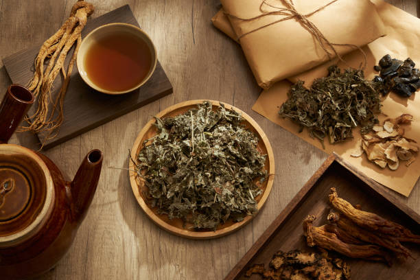 TRADITIONAL MEDICINE Dry mug wort on round dishes in the middle, medicine package, potion decoction and herbs placed on wooden table background. Scene for medicine advertising chinese herbal medicine stock pictures, royalty-free photos & images