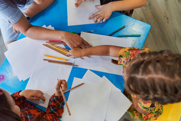 istock Creative kids during an art class in a daycare center or elementary school classroom drawing with female teacher. 1490583905