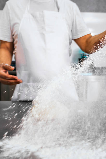 istock Master Baker. Baker man pours flour on the table to make bread. 1490584078