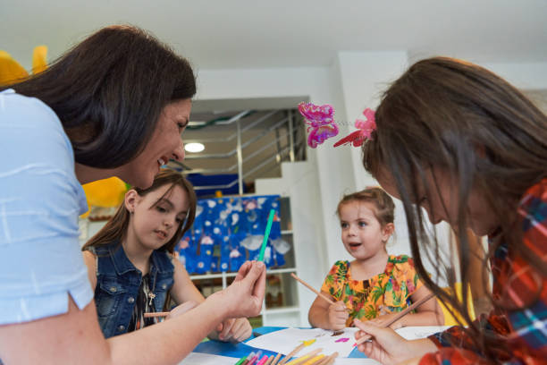 istock Creative kids during an art class in a daycare center or elementary school classroom drawing with female teacher. 1490585306