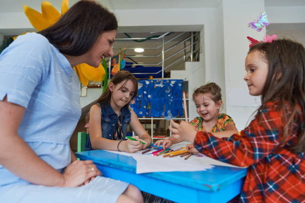 istock Creative kids during an art class in a daycare center or elementary school classroom drawing with female teacher. 1490586057