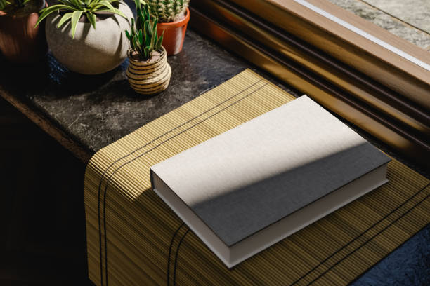 istock Hard cover book mock up near a window. Daylight interior with plants. 3D rendering 1490586081