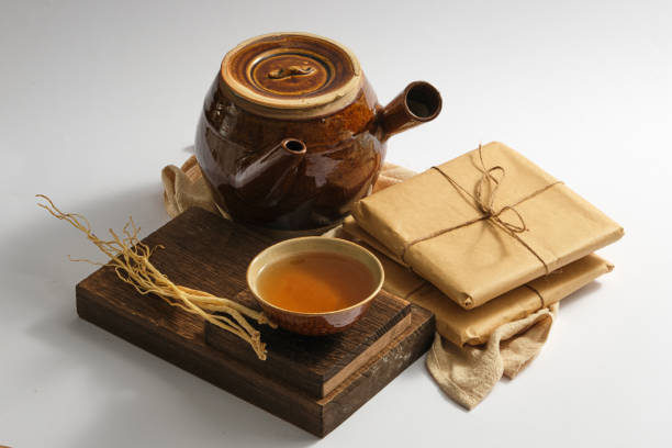 TRADITIONAL MEDICINE A wooden podium with a bowl of medicine and Dang Shen placed on, displayed with an earthen pot and some medicine packs. Chinese herbal therapy codonopsis pilosula stock pictures, royalty-free photos & images