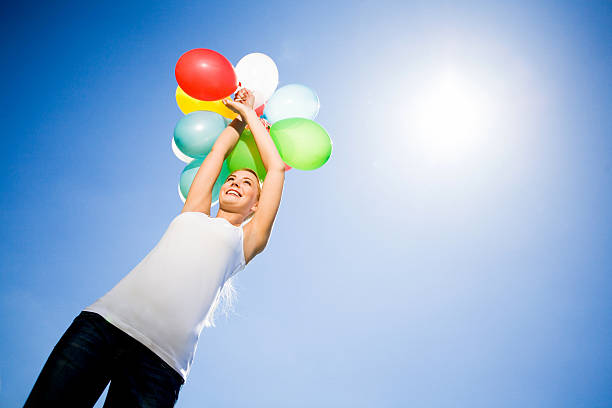 istock Woman holding balloons against blue sky 149058982