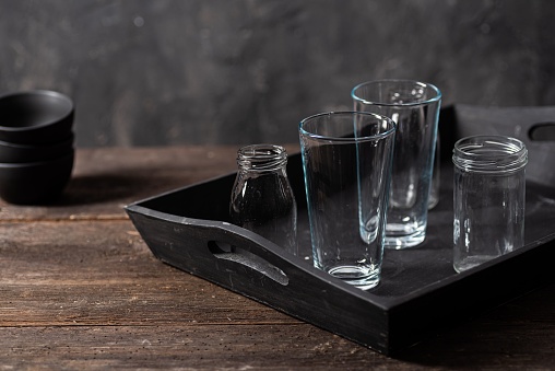Closeup of a black tray with empty glasses on a wooden surface
