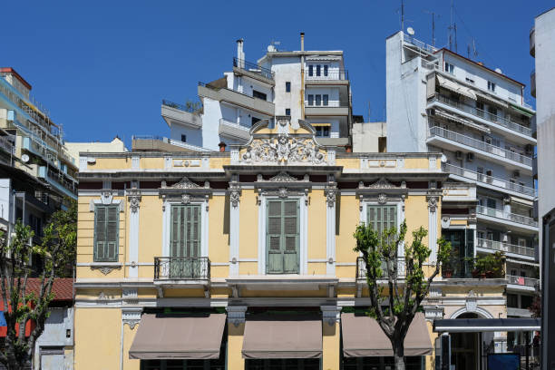 istock Traditional building with decoration and vintage shutters between modern unadorned apartment houses on a sunny day with blue sky in the city center of Thessaloniki, Greece 1490597786