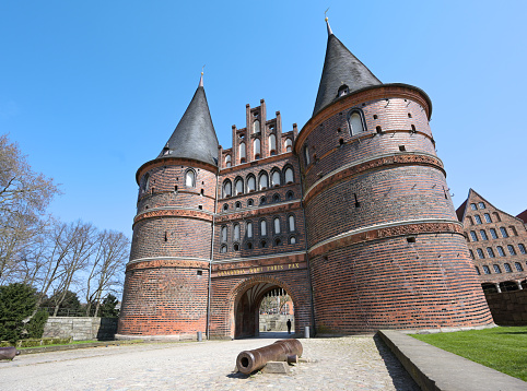 Lubeck Holstentor (Holsten gate) with canon, famous historic landmark with two round towers and an arched entrance to the hanseatic German city, gothic brick architecture from medieval times
